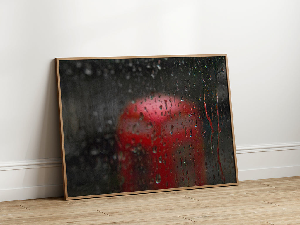 Rainy window with a blurred red postbox visible in the background, creating a moody and nostalgic atmosphere.